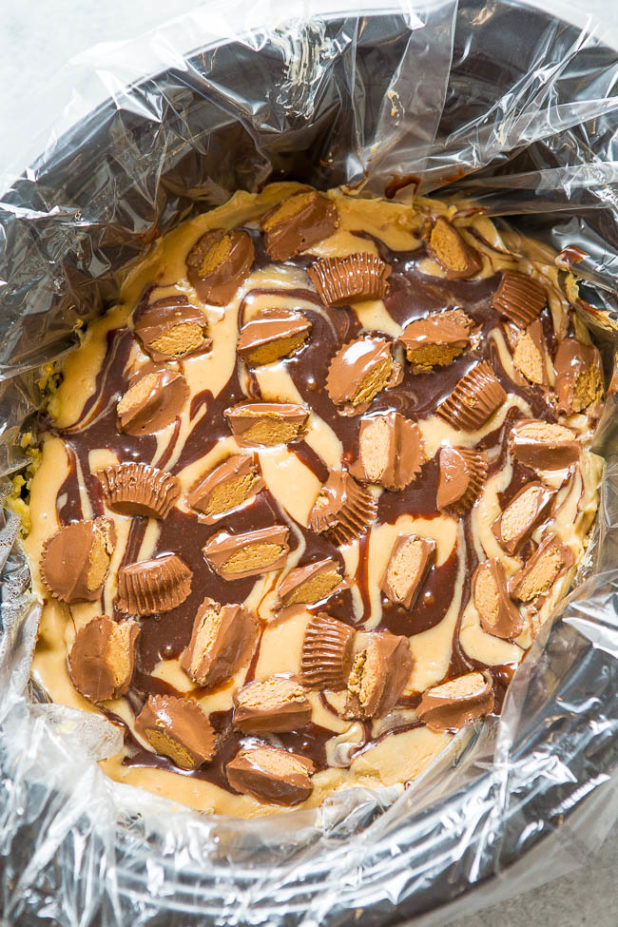 Yellow cake is spiked with peanut butter, hot fudge, topped with a peanut butter glaze, more hot fudge, and sprinkled with peanut butter cups!! It’s rich, decadent, SO EASY, and made in a slow cooker!!